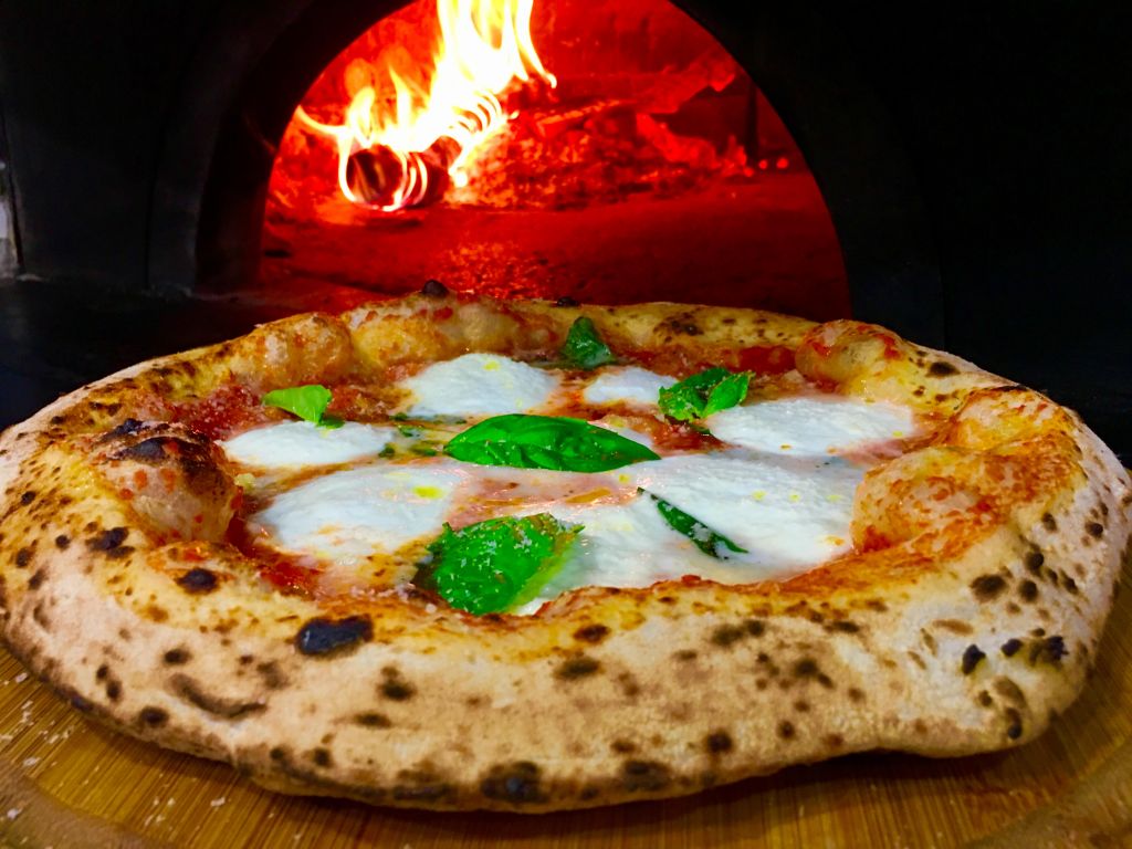 Pizza margherita napoletana appena sfornata dal forno a legna in una pizzeria di Napoli