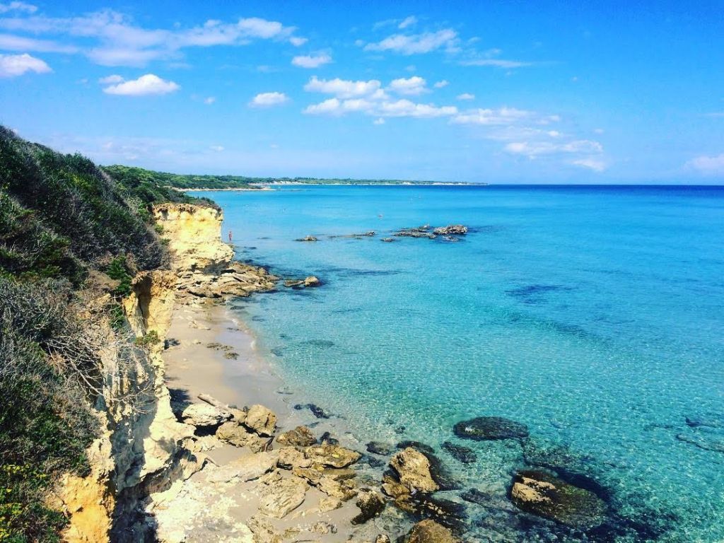 Spiaggia pugliese con acque cristalline e costa rocciosa nel Salento