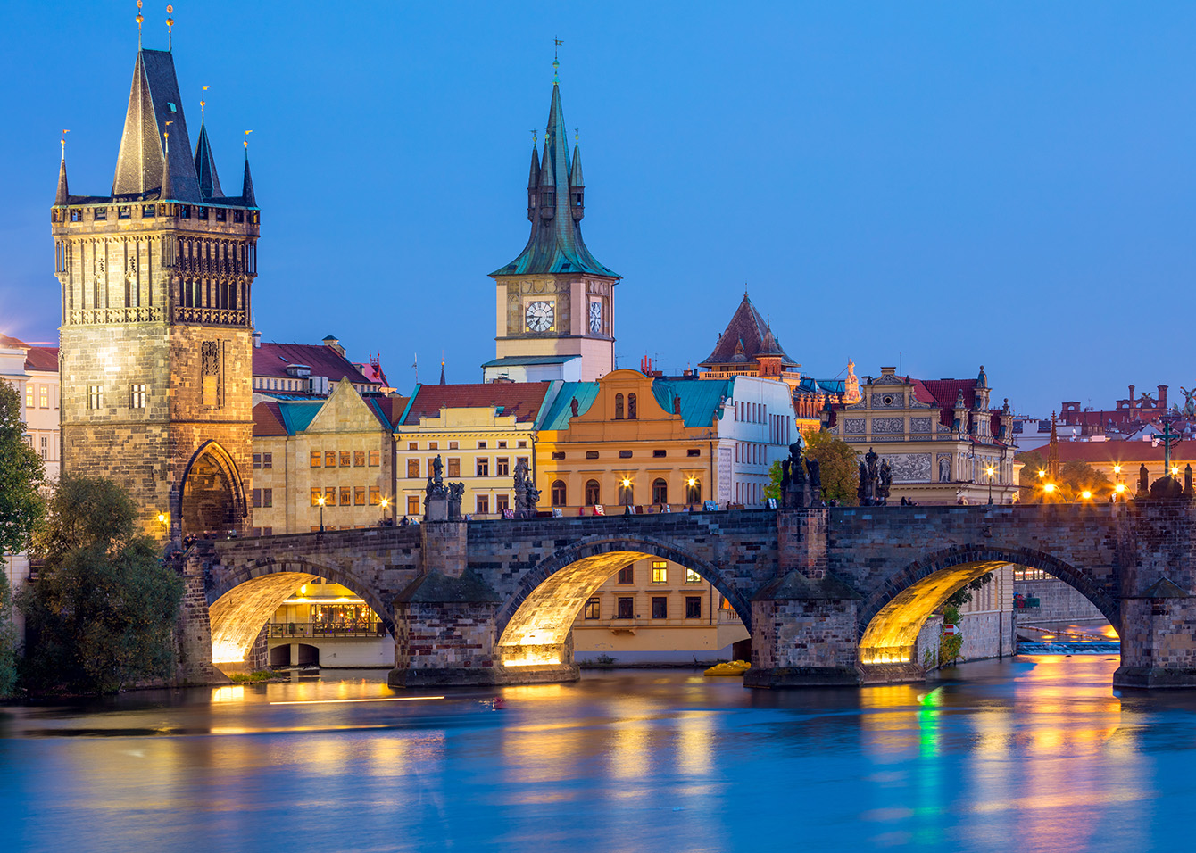 Il Ponte Carlo di Praga sul fiume Moldava con il Castello sullo sfondo al tramonto