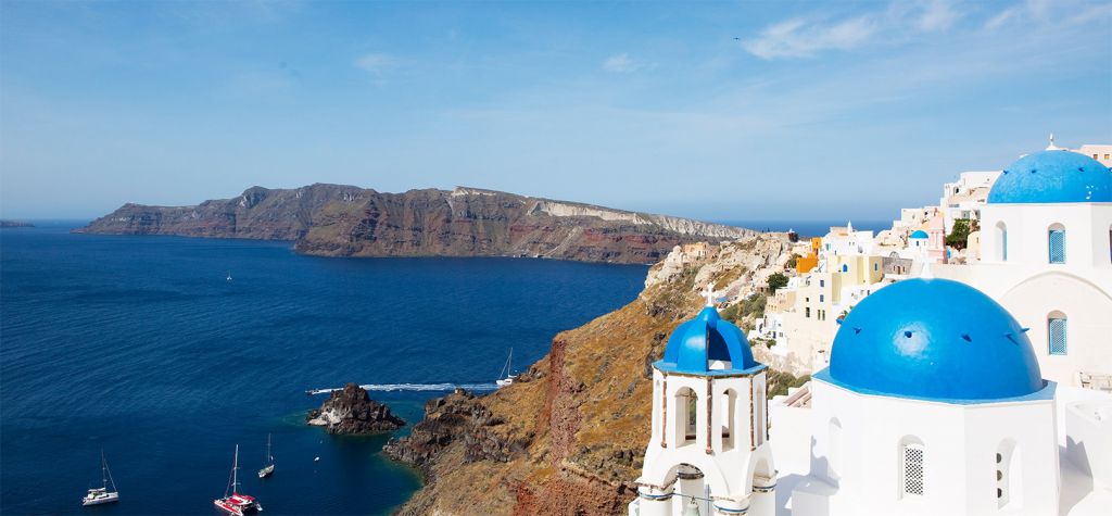 Le case bianche con cupole blu di Santorini affacciate sulla caldera al tramonto, in Grecia