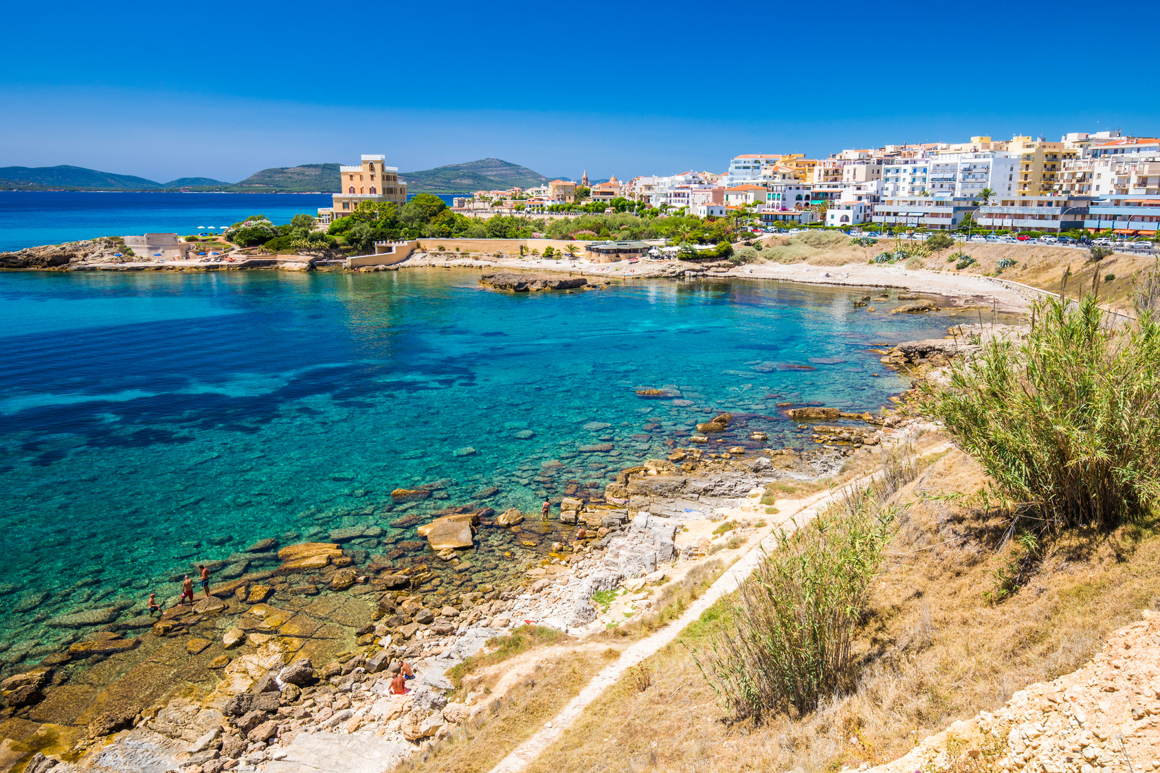 Veduta del centro storico di Alghero affacciato sul mare turchese della Sardegna