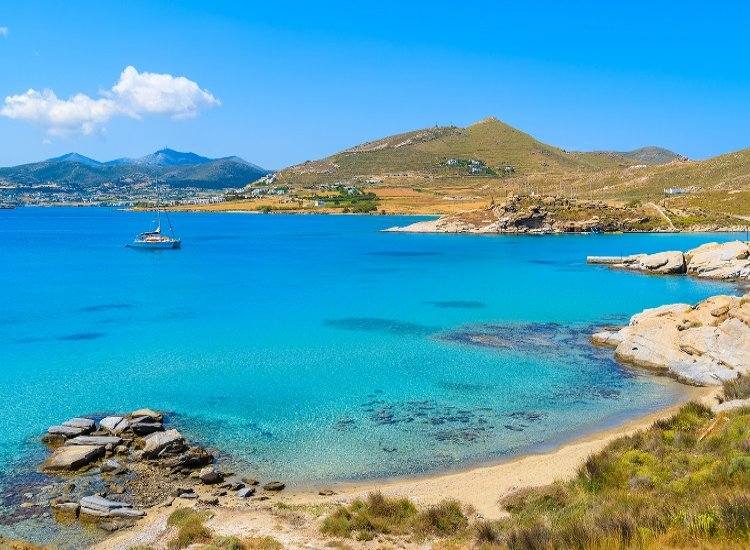 Una spiaggia di Paros con il mare azzurro dell'Egeo e le case bianche