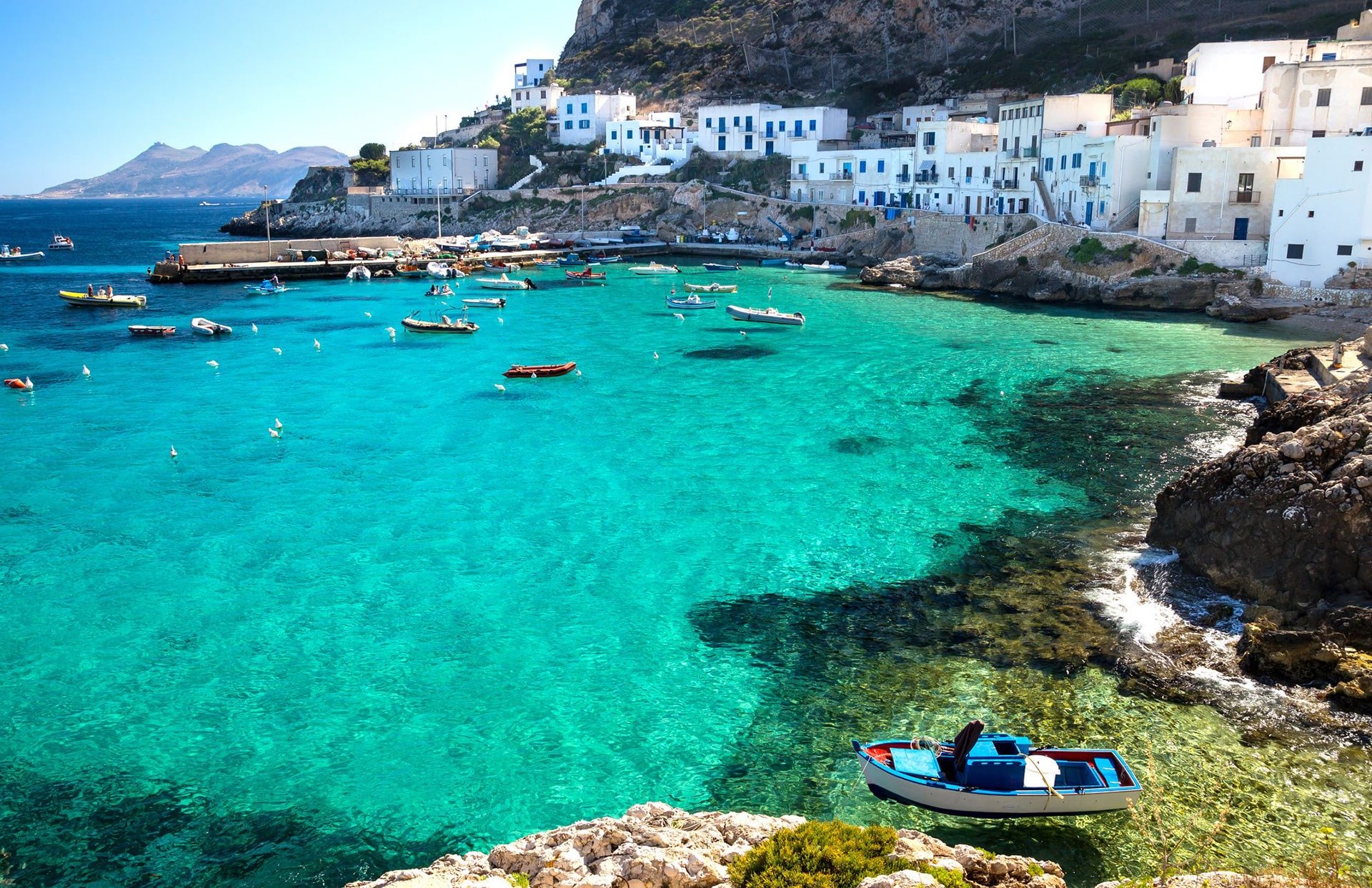 Caletta dal mare cristallino e case bianche dell'isola di Levanzo alle Egadi