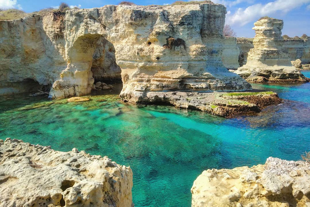 Spiaggia con acque cristalline e scogliera nel Salento, Puglia
