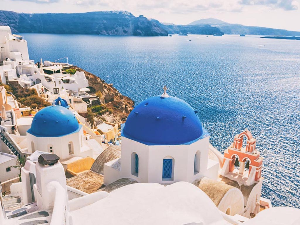 Case bianche con cupole blu su un'isola della Grecia affacciate sul mare